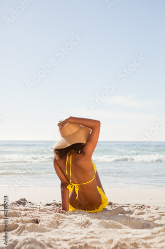 Photo: Rear view of an attractive woman holding her hat while looking at the ocean Rear view of an attractive woman holding her hat while looking at the ocean