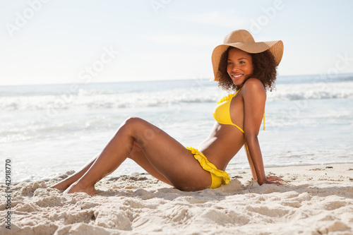Photo: Side view of a young smiling woman sitting in front of the ocean Side view of a young smiling woman sitting in front of the ocean