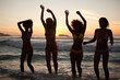 Young women raising their arms above their heads on the beach