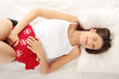 Young woman is lying and showing stomachache.