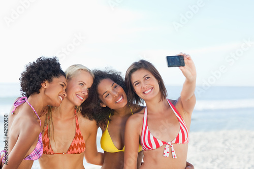 Photo: Four friends posing for a photo on the beach Four friends posing for a photo on the beach