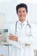 Smiling doctor crossing his arms as he looks ahead