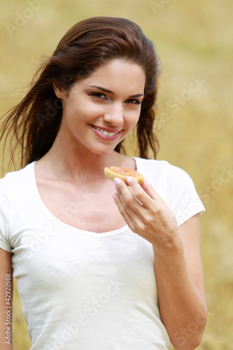 Photo: Jeune femme mangeant une tartine dans un champ de blé Jeune femme mangeant une tartine dans un champ de blé