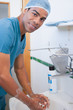Happy male surgeon washing his hands with soap