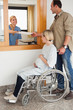 Nurse giving a paper to a man and a pregnant woman in a wheelchair