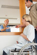 Smiling nurse giving a paper to a man and a woman in a wheelchair
