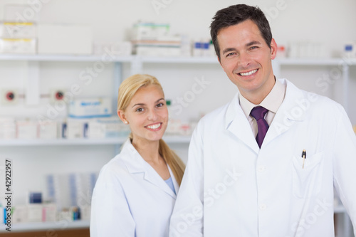 Photo: Two pharmacists standing behind a counter Two pharmacists standing behind a counter
