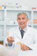 Smiling pharmacist taking a prescription from the hand of a customer