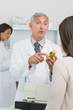 Pharmacist with a customer pointing at a flask of pills