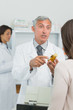 Pharmacist holding a flask of pills in front of a customer