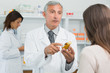 Pharmacist talking to a customer while holding a flask of pills