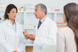 Pharmacist talking to a colleague in front of a patient