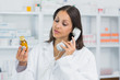 Female pharmacist holding a bottle of pills while on the phone