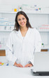 Smiling female pharmacist standing behind the counter of a pharmacy