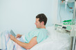 Male patient touching a tactile tablet while lying on a bed