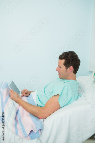Photo: Patient touching a tactile tablet while lying on a bed Patient touching a tactile tablet while lying on a bed