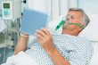 Senior patient lying on a bed with a mask while holding a tactile tablet