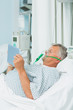 Senior male patient wearing an oxygen mask while using a tactile tablet