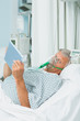 Photo: Senior male patient wearing an oxygen mask while holding a tactile tablet in his hands Senior male patient wearing an oxygen mask while holding a tactile tablet in his hands