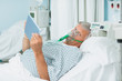 Photo: Senior patient holding a tactile tablet in his hands while wearing an oxygen mask Senior patient holding a tactile tablet in his hands while wearing an oxygen mask