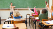 Back view of primary school class raising hands
