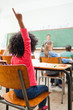 Back view of schoolgirl raising hand during class