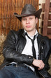 Foto: Handsome young cowboy with traditional outfit sitting on hay. Handsome young cowboy with traditional outfit sitting on hay.