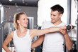 Trainer helping a woman work out with dumbbells