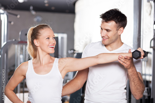 Photo: Trainer helping a woman work out with dumbbells Trainer helping a woman work out with dumbbells