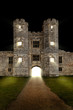Old castle at night with lights shining through open door
