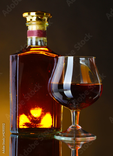 Foto: Glass of brandy and bottle on brown background Glass of brandy and bottle on brown background