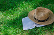 Book and straw hat on grass