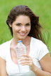 Jeune femme brune souriante buvant de l'eau dans un champ