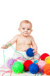 Smiling baby plays with colored balls of yarn