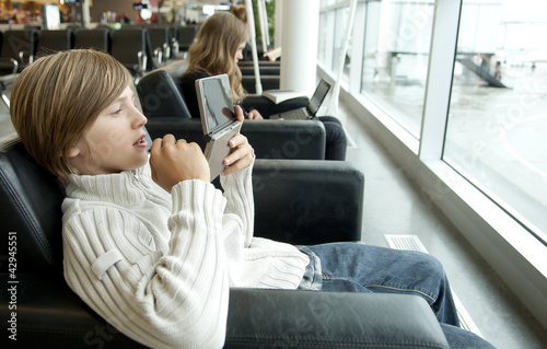 Photo: Young boy playing with a console in airport Young boy playing with a console in airport