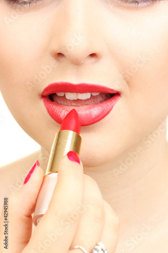 Foto: beautiful woman is applying her lips with red lipstick beautiful woman is applying her lips with red lipstick