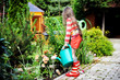 Photo: Little girl in a garden with green watering can Little girl in a garden with green watering can