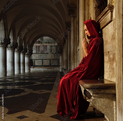 Foto: Woman in red cloak praying alone Woman in red cloak praying alone