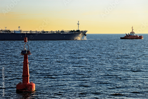 Foto: Red buoy on the fairway and outbound tanker in the sea Red buoy on the fairway and outbound tanker in the sea