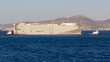 A large vehicles carrier ship pushed to port by two tug boats