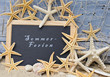Sommer-Ferien: Tafel mit Seesternen vor blauer Wand