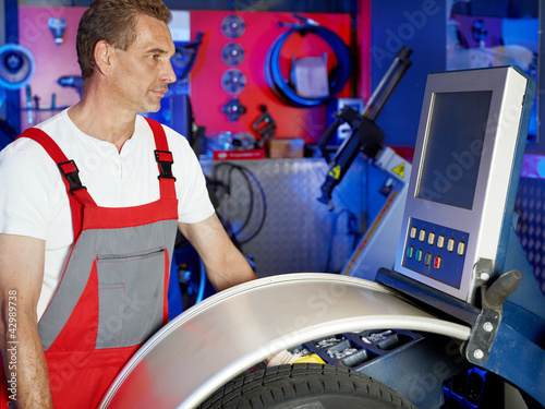 Foto: Motor mechanic fitting a tyre in a garage with counterbalancing Motor mechanic fitting a tyre in a garage with counterbalancing