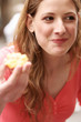 A lady smiling while eating a biscuit
