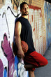 A basketball player holding a ball leaning against a mural