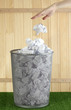 hand going garbage in metal trash bin from paper