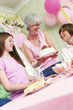 A woman bringing out a birthday cake for her daughter