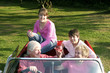 An old couple taking their grandchildren for a car ride