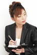 Studio shot of a lady in office attire writing on her organizer