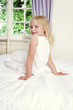 Back shot of a girl sitting on the bed while flashing a smile at the camera