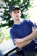 A boy with cap leaning against a car 